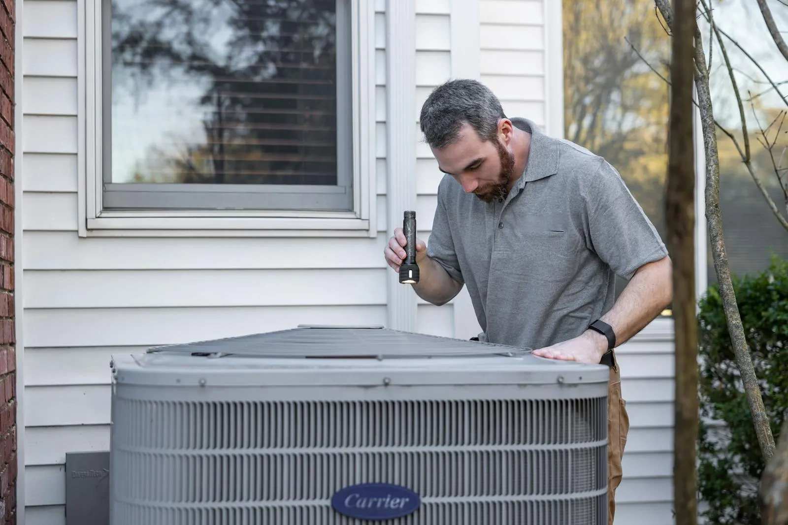 HVAC technician inspecting a residential outdoor condenser